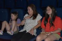 Na zdjęciu trzy osoby z publiczności na fotelach oglądające przedstawienie w MOK.