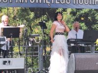 Muzycy grający na instrumentach i wokalistka śpiewająca podczas występu na scenie w Lutkówce.