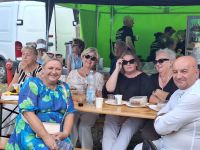 Uczestnicy Odpustu na Świętego Rocha w Lutkówce odpoczywają siedząc na krzesełkach.