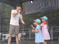 Wokalista śpiewający podczas Odpustu na Świętego Rocha w Lutkówce i dwoje dzieci zaproszonych na scenę.