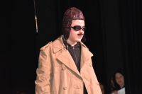 Aktor w przebraniu mężczyzny (wąsy, płaszcz) na scenie MOK, podczas występu.