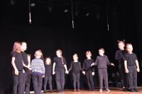 Grupa dzieci podczas przedstawienia na scenie: chłopcy i dziewczynki.