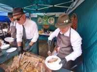 Rozdawanie porcji upieczonego dzika przez lokalnych przedstawicieli kół łowieckich.