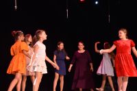 Młode aktorki z grupy teatralnej tańczące na scenie.